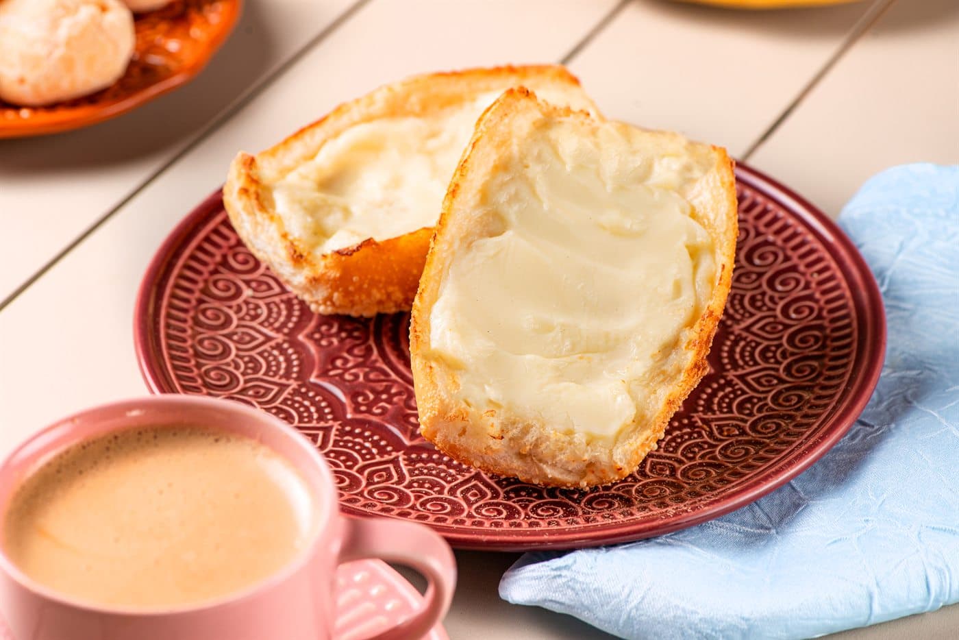 Pão na chapa com manteiga e café, servidos na janela.