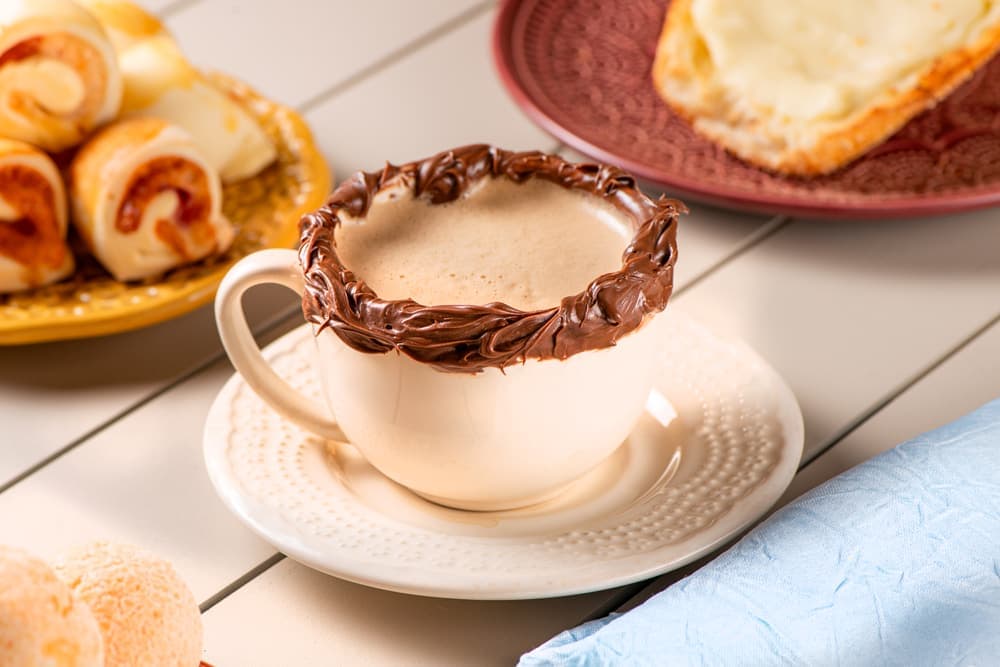 Cappuccino com calda de chocolate em xícara branca.