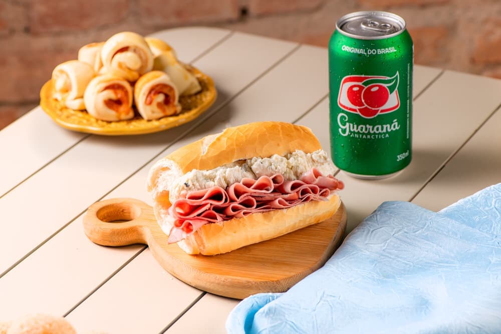 Sanduíche de mortadela com queijo no pão francês, com guaraná.