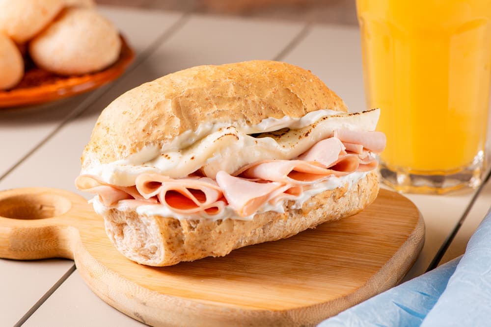 Sanduíche de peito de peru com queijo, com suco de laranja.
