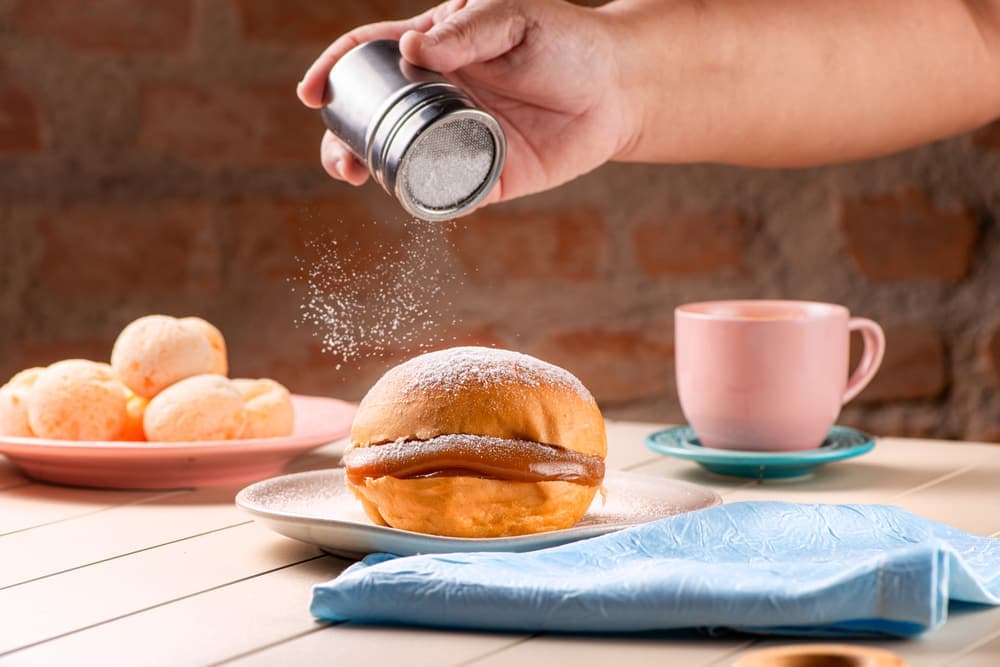Sonho sendo polvilhado de açúcar, com café.