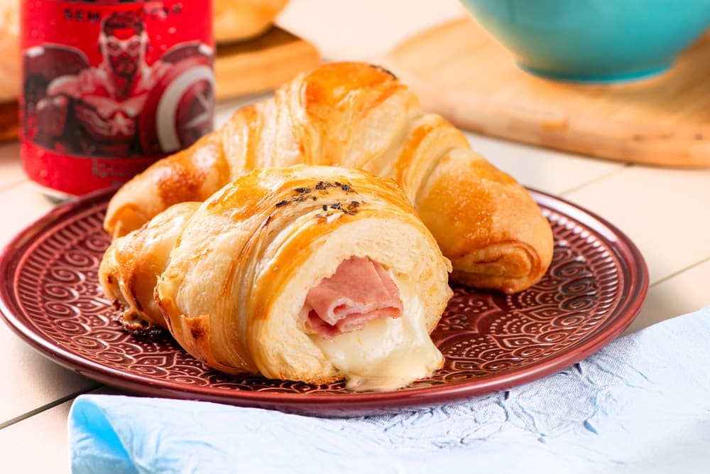 Croissant de presunto e queijo em prato vermelho.