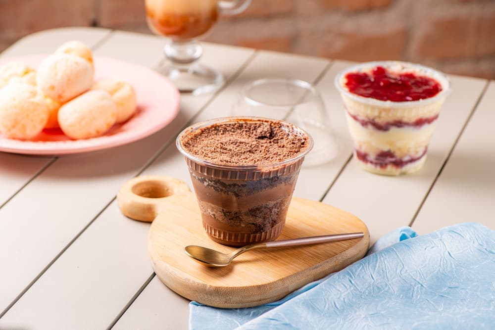 Copos de sobremesa de morango e chocolate, com pães de queijo.