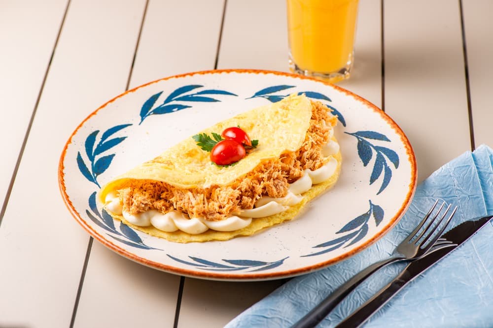 Omelete de frango em prato azul, com suco de laranja.