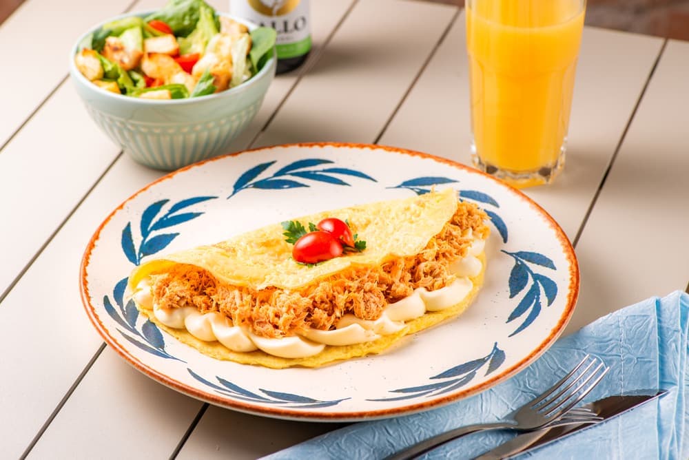 Omelete de frango em prato azul, com suco de laranja.