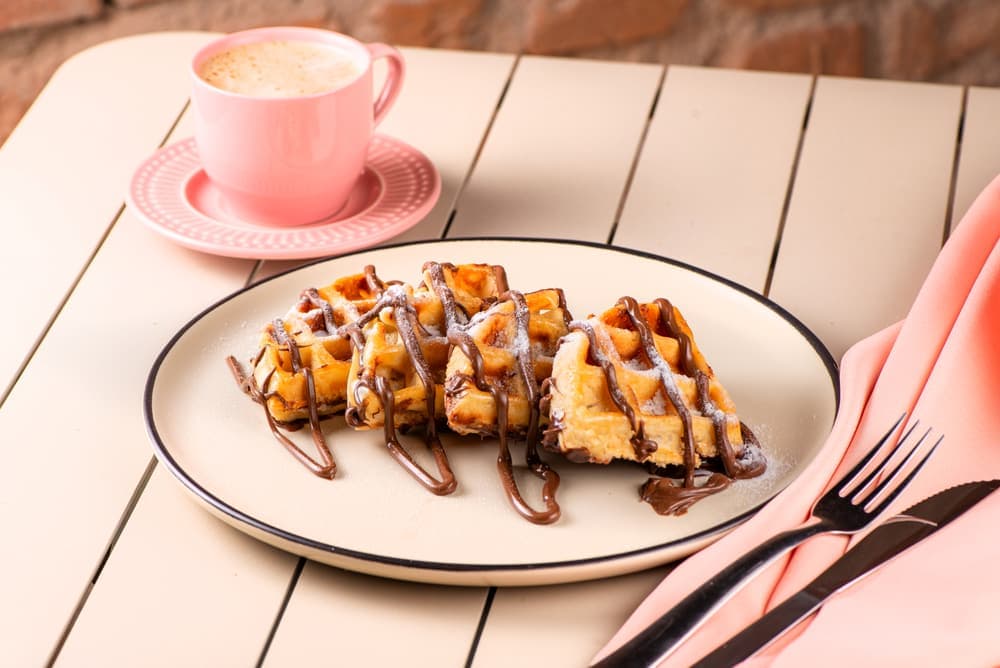 Waffle com calda de chocolate e banana, com café.