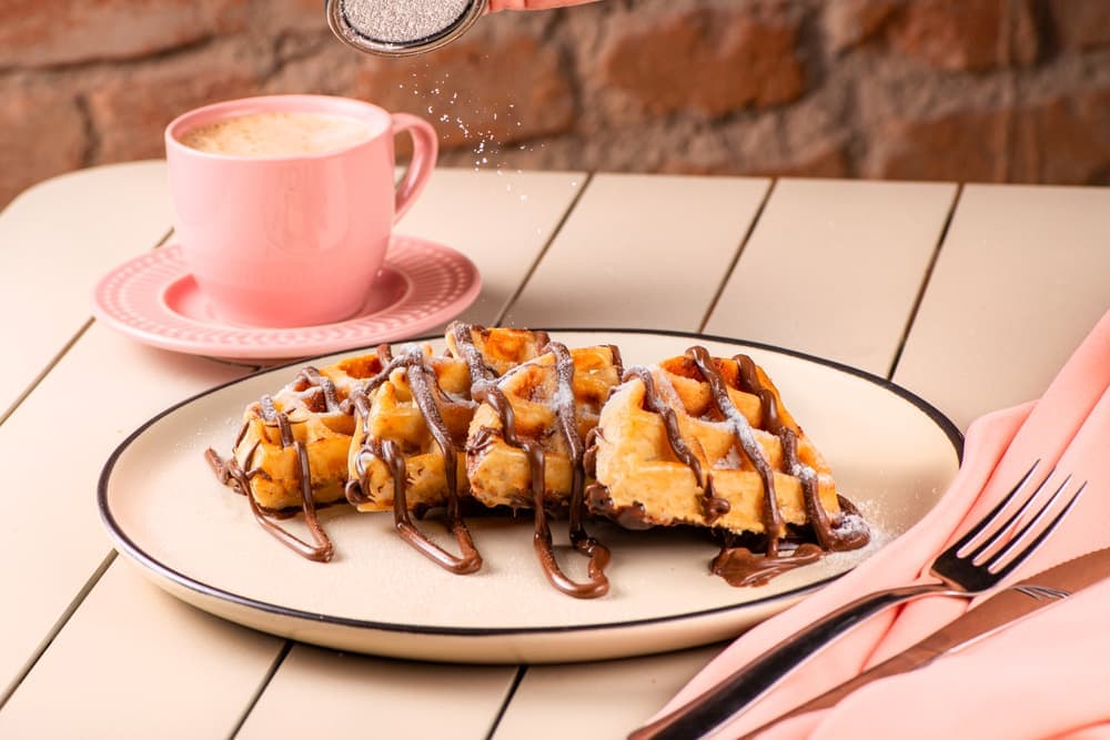 Waffle com calda de chocolate e banana, com café.