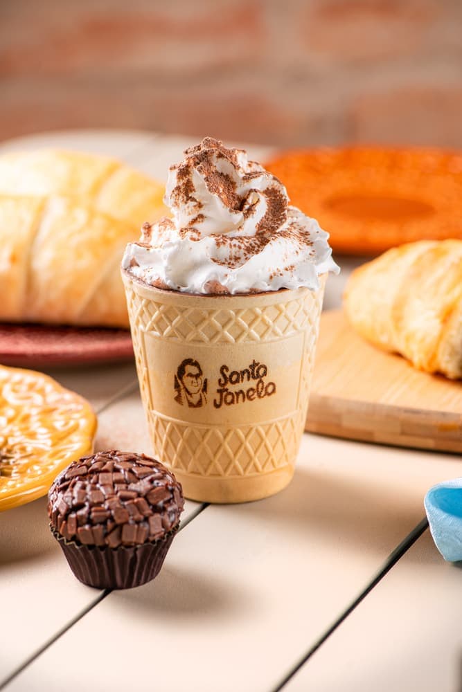 Chocolate quente com chantilly no copo Santa Janela, com croissants.