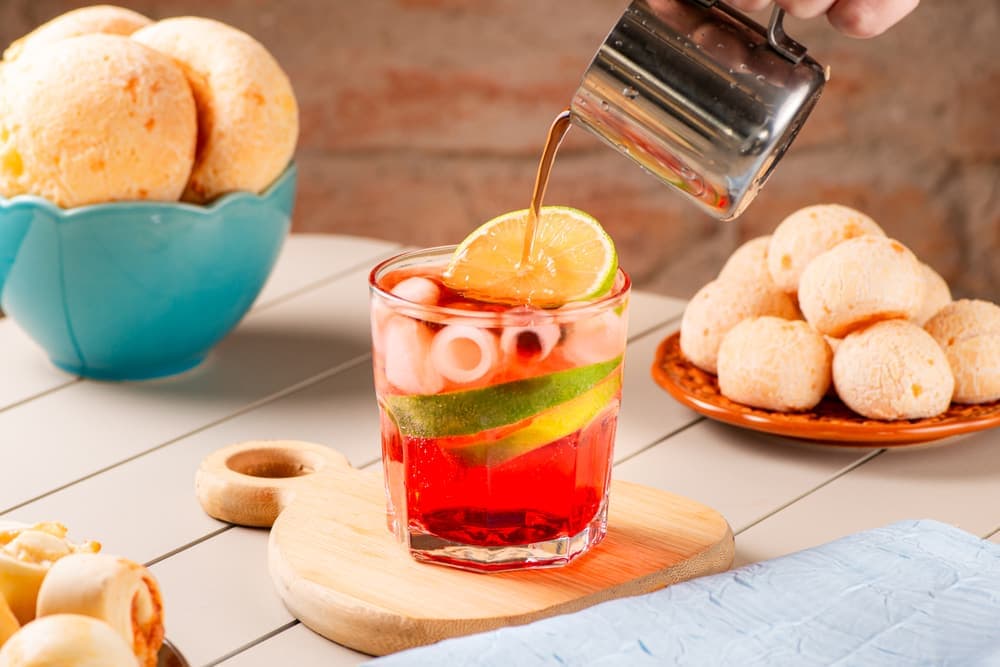 Suco de morango com limão sendo servido, com pães de queijo.