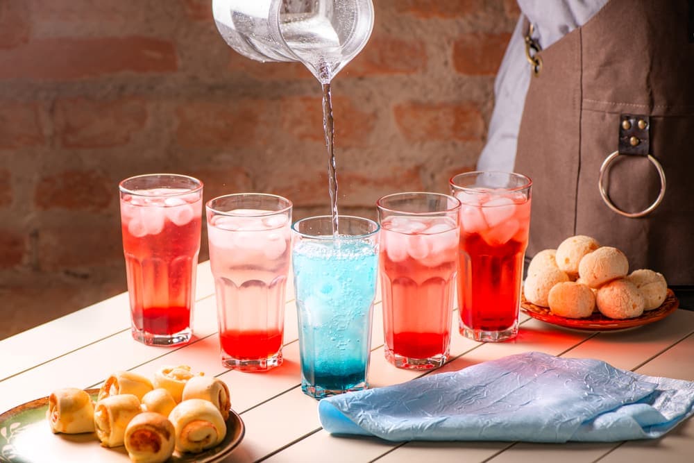 Sucos e refrescos coloridos em copos, com enroladinhos.