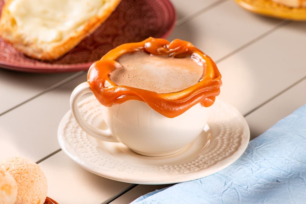 Cappuccino com calda de caramelo em xícara branca.